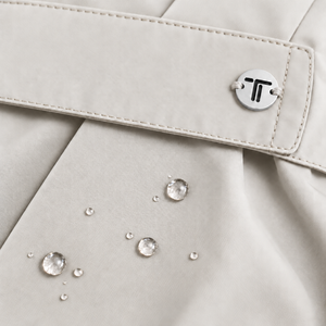 Dettaglio giacca beige chiaro: patta con fibbia metallica e punti decorativi